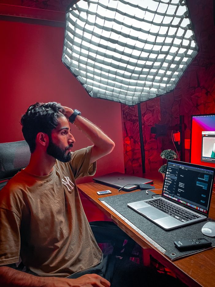 A programmer working late at night with a laptop in a dimly lit studio setting.