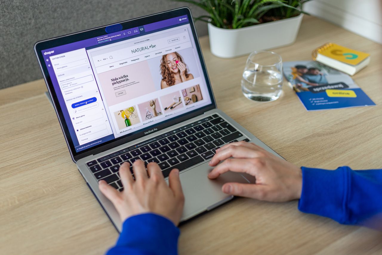 The Art of Drawing Readers In: Your attractive post title goes here Hands typing on a laptop showing an e-commerce website in a modern office setting.