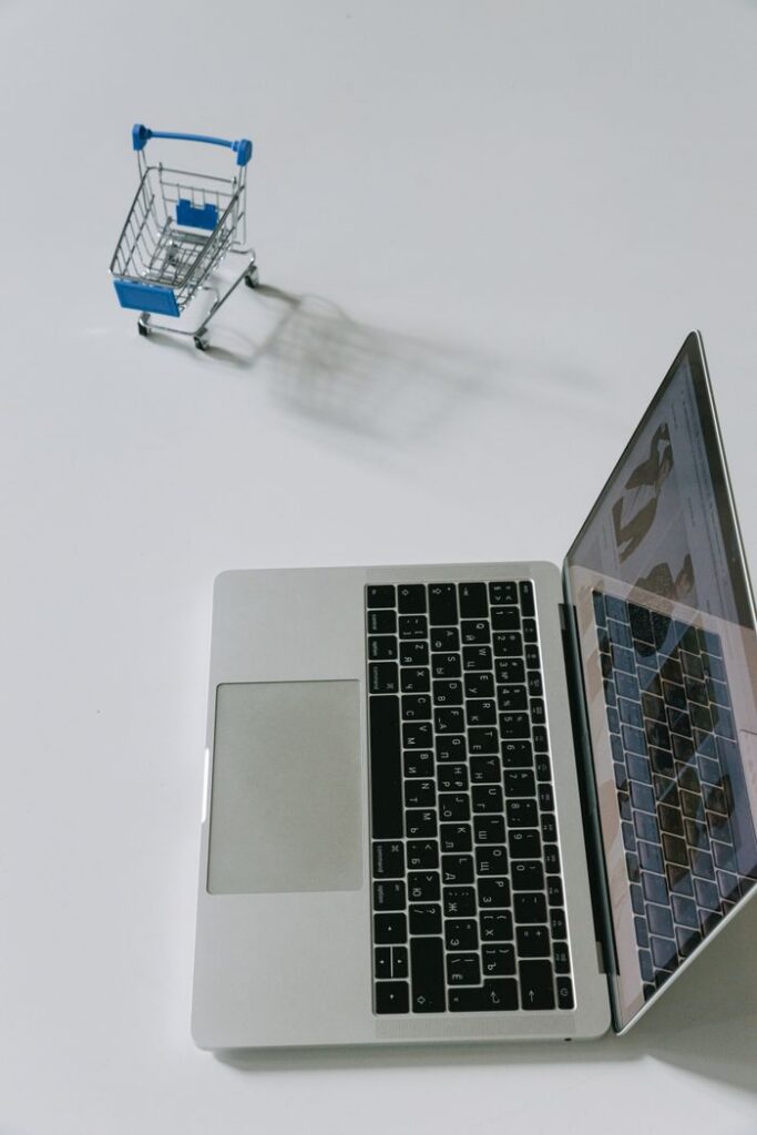 Mastering the First Impression: Your intriguing post title goes here Minimalist scene of a laptop beside a miniature shopping cart symbolizing online shopping.