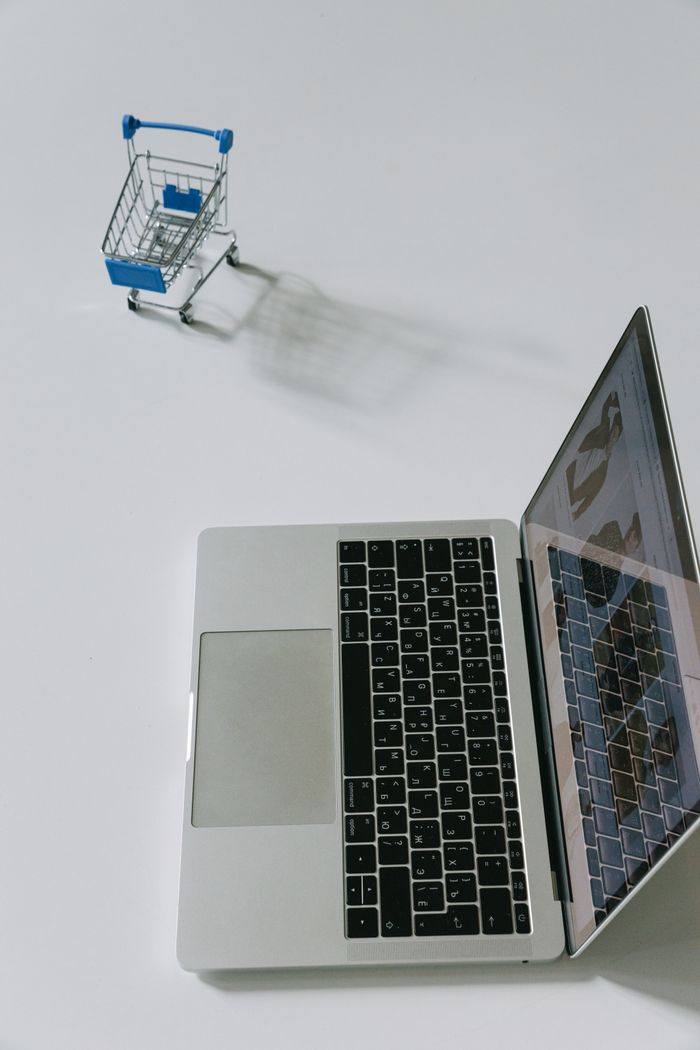 Mastering the First Impression: Your intriguing post title goes here Minimalist scene of a laptop beside a miniature shopping cart symbolizing online shopping.